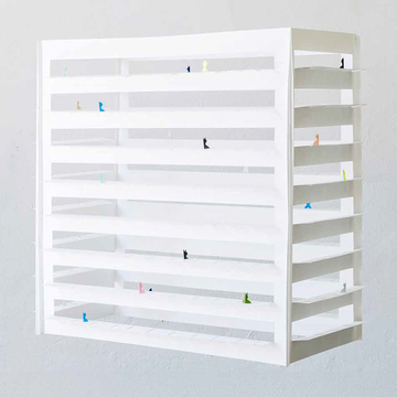 Installation in weiß, möglicherweise als Hochhaus mit großen freien Flächen für viel Licht und Lücken in denen sich bunte Gestalten bewegen. 