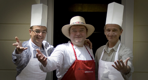 Titus Giese, Wiglaf Droste und Peter Böthig stehen nebeneinander und strecken dem Betrachter den Arm entgegen. Alle drei tragen Kochschürzen, Giese und Böthig außerdem eine Kochmütze.